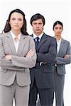 Serious salesteam standing together with arms folded against a white background