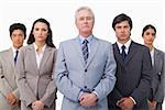 Mature businessman standing with his colleagues against a white background