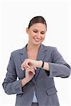 Smiling businesswoman looking at her watch against a white background