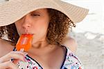 Attractive young woman wearing a straw hat while eating a delicious popsicle