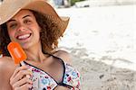 Smiling woman showing a beaming smile while holding a delicious orange popsicle