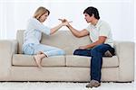 A couple sitting on a couch are looking at each other and pointing