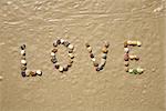 Love word writing with small stones on sand beach ground