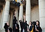 Happy graduates throwing their hats in the sky in front of their university