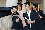 Close-up of a female graduate taking a picture of her friend in front of the university