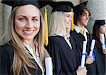 Close-up of a beautiful graduate with blue eyes next to her friends posing