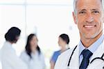 Doctor showing a beaming smile with his medical interns behind him