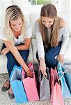 A pair of smiling girls looking into their shopping bags