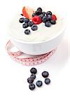 Berries cream in a bowl with a tape measure against a white background