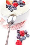 Berries cream and spoon with a tape measure  against a white background