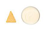 A bowl of white dip and a nacho placed side by side