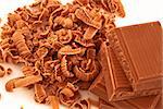 Chocolate shavings surrounding a pile of chocolate against a white background