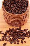 Close up of a basket filled with coffee seeds on a wooden tablecloth against a white background