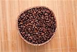 Many roasted coffee seeds in a wooden basket