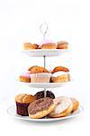 Many cakes placed on three white plates against a white background