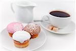 Small muffins and coffee on white plate with sugar and milk against a white background