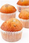 Four small baked muffins against a white background