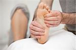 Chiropodist palpating the sole of the foot of a patient in his office