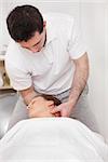 Therapist manipulating the neck of his patient while standing in a room