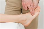 Fingers of a physiotherapist pressing on a foot in a room