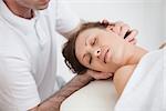 Woman being massaging by the doctor while having the head turn in the side inddor