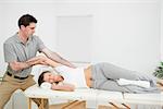 Chiropractor stretching the arm of his patient while holding it in a room