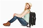 Tired woman sitting against a suitcase against white background