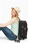 Blonde-haired woman sitting against a suitcase against white background