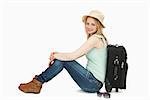 Cheerful woman sitting near a suitcase against white background