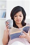 Woman holding a mug while reading a book in a living room