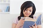 Woman reading a book while holding a cup in a living room