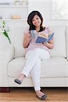 Woman smiling and reading a book in living room