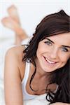 Smiling brunette woman lying on her quilt in her bedroom