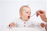 Baby being fed by her mother against a grey background