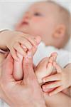 Hands touching the feet of a baby against a grey background