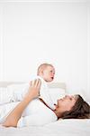 Cheerful woman holding her cute little girl in a bedroom