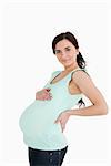 Pregnant woman holding her back against white background