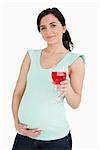 Pregnant woman holding a mocktail against white background