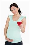 Young pregnant woman holding a mocktail against white background