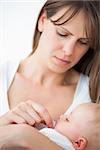 Serious woman giving a pacifier to her daughter against a grey background