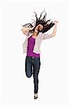 Brunette jumping with her hair in the air against white background