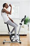 Side view of a black woman on an exercise bike in a living room