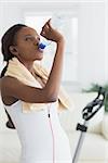 Black woman drinking water in a living room