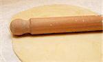 Fresh pastry rolled out on a floured surface with a wooden rolling pin