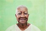 Old black woman portrait, lady in elegant clothes smiling on green background. Copy space