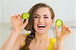 Smiling young woman showing slices of cucumber