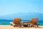 Beach chairs on perfect tropical yellow sand beach with blue sea and island on background, Gili, Bali, Indonesia
