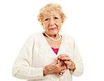 Senior woman with arthritis is having trouble buttoning her sweater. Isolated on white.