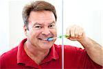 Happy, smiling man brushing his straight white teeth.