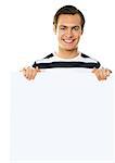 Casual young man holding a blank poster against white background